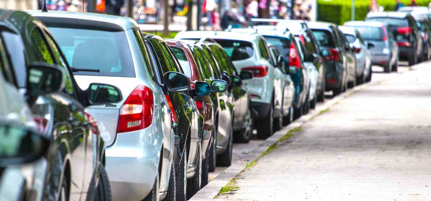 Auto parcheggiate lungo marciapiede in un comune italiano, rispettando le linee di sosta indicate.