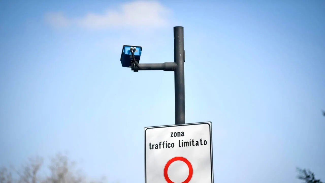 Cartello Zona traffico limitato con telecamera di sorveglianza su un palo, cielo azzurro sullo sfondo.